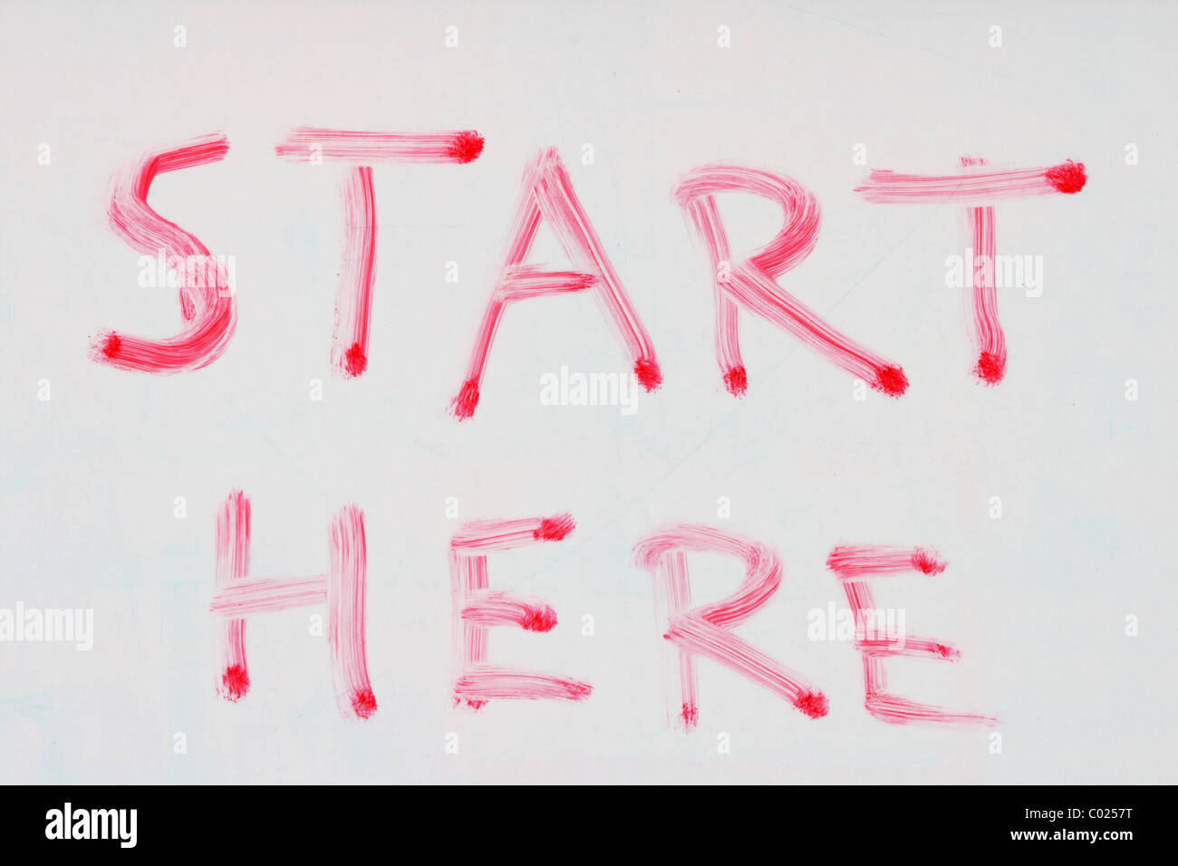 start here written in red dry erase marker on a used white board Stock Photo