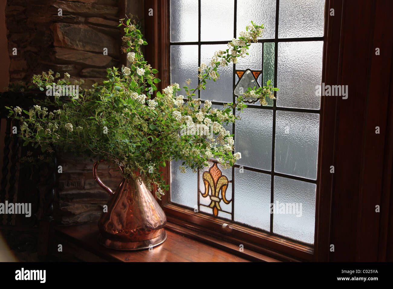Flower display in brass vase on window sill Stock Photo