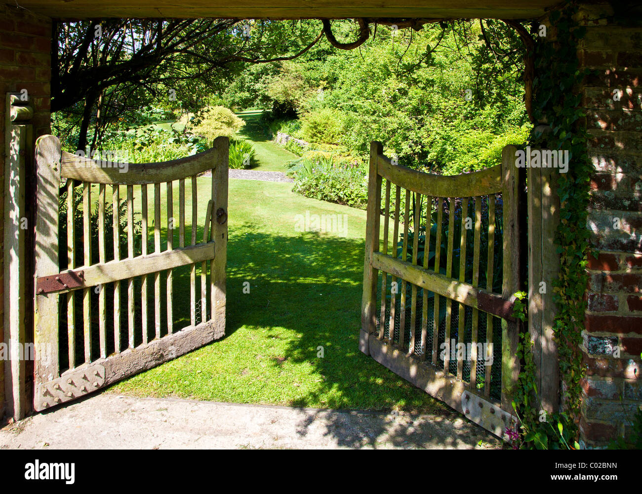 An open wooden garden gate in an English country garden showing a view to the wider garden beyond. Stock Photo