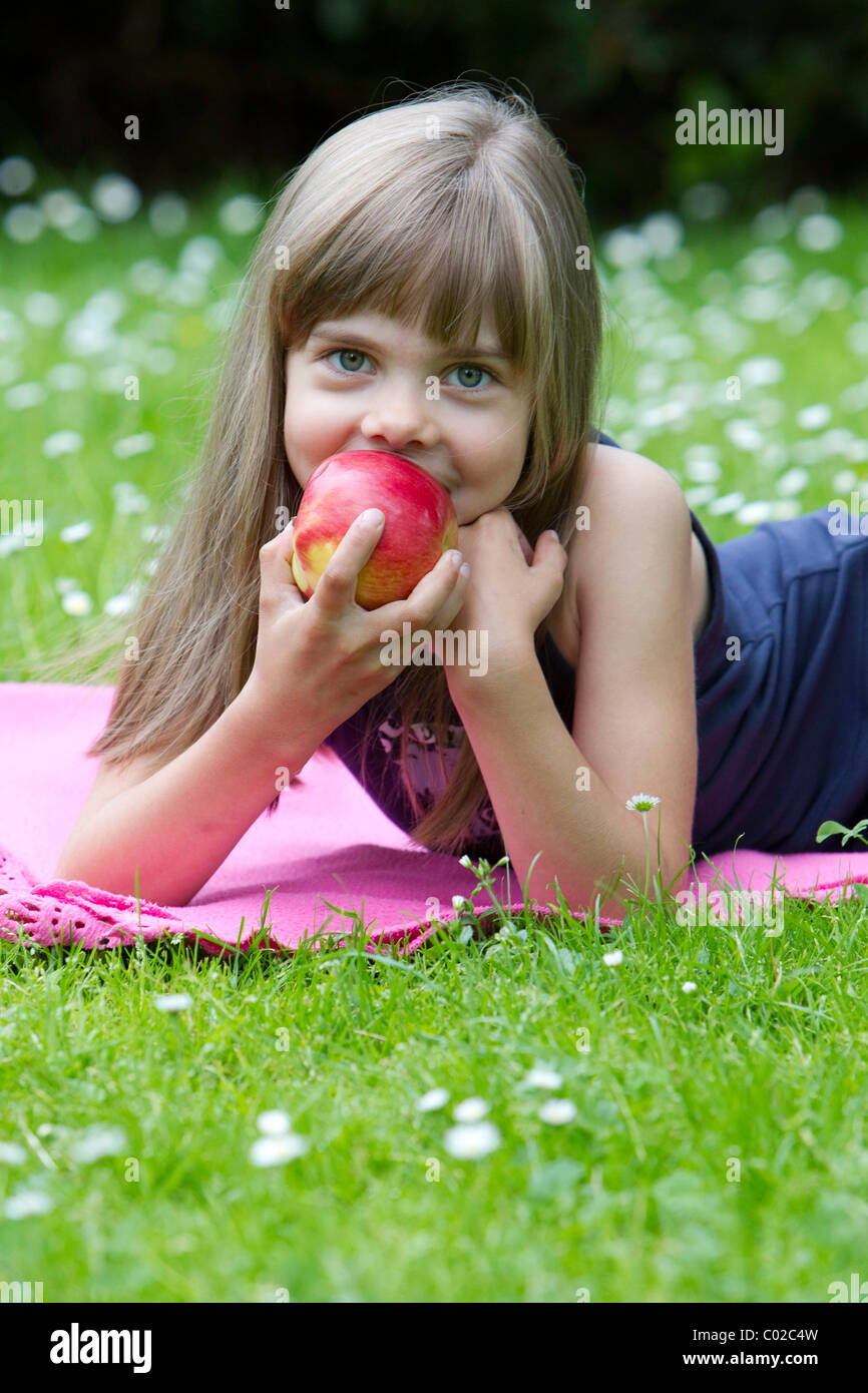 Little girl lying on a blanket eating an apple Stock Photo Alamy
