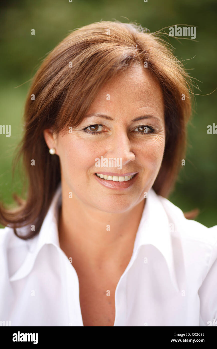 Woman, 45 years, wearing a light blouse in natural surroundings Stock Photo