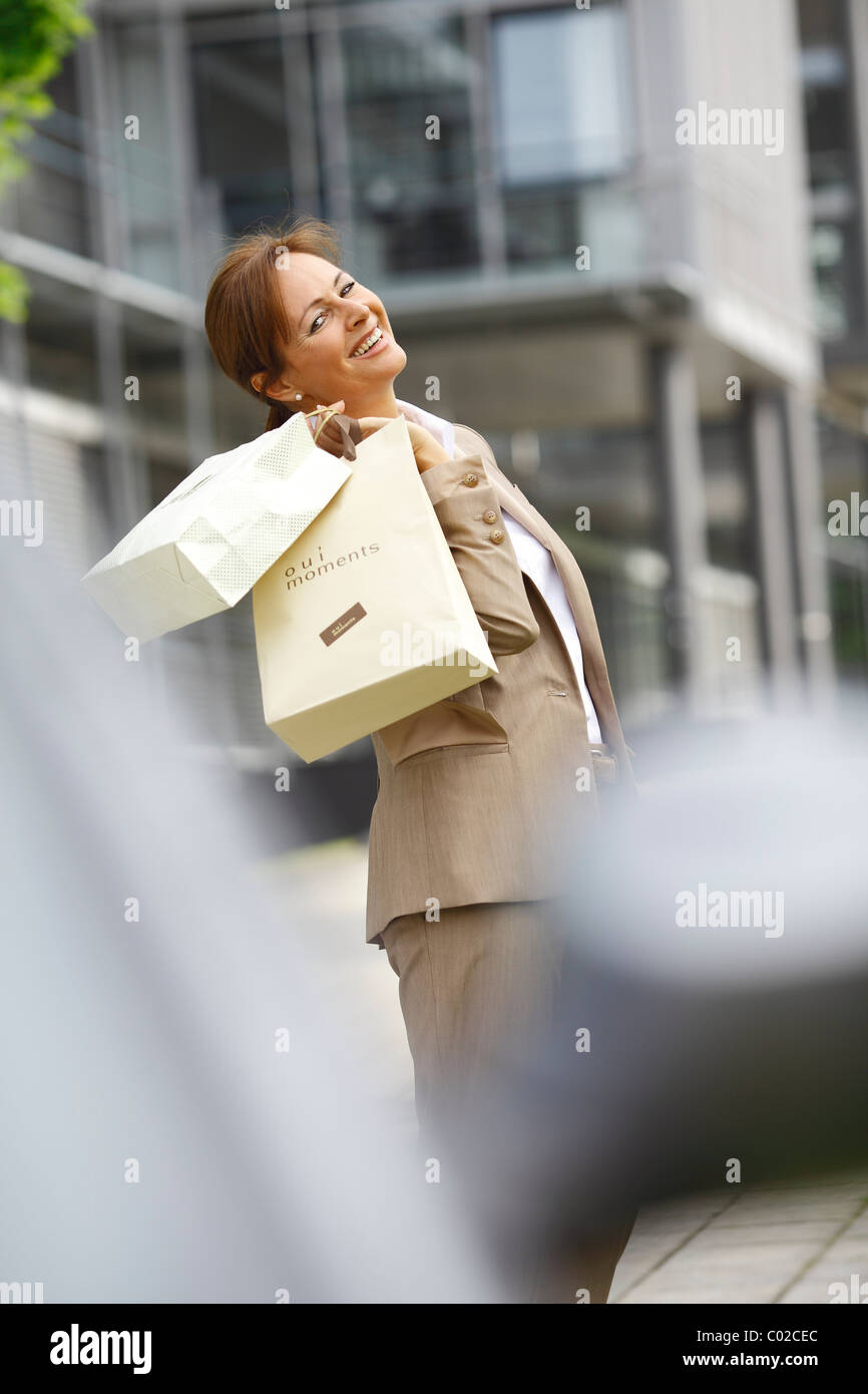 Smiling business woman, 45 years, carrying shopping bags Stock Photo