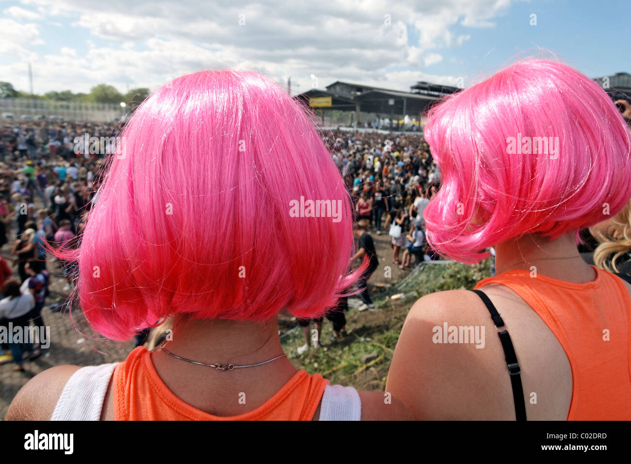 Two young female ravers wearing whacky wigs watching the crowds, Loveparade 2010, Duisburg, North Rhine-Westfalia Stock Photo