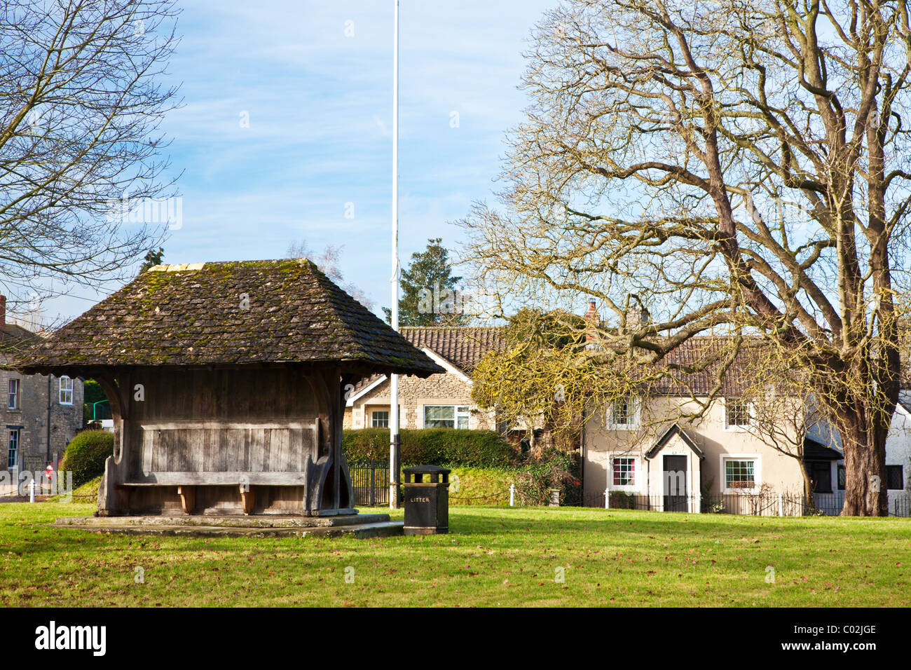The village green, known as Ham Green, with flagpole and bench, in the village of Holt, Wiltshire, England, UK Stock Photo
