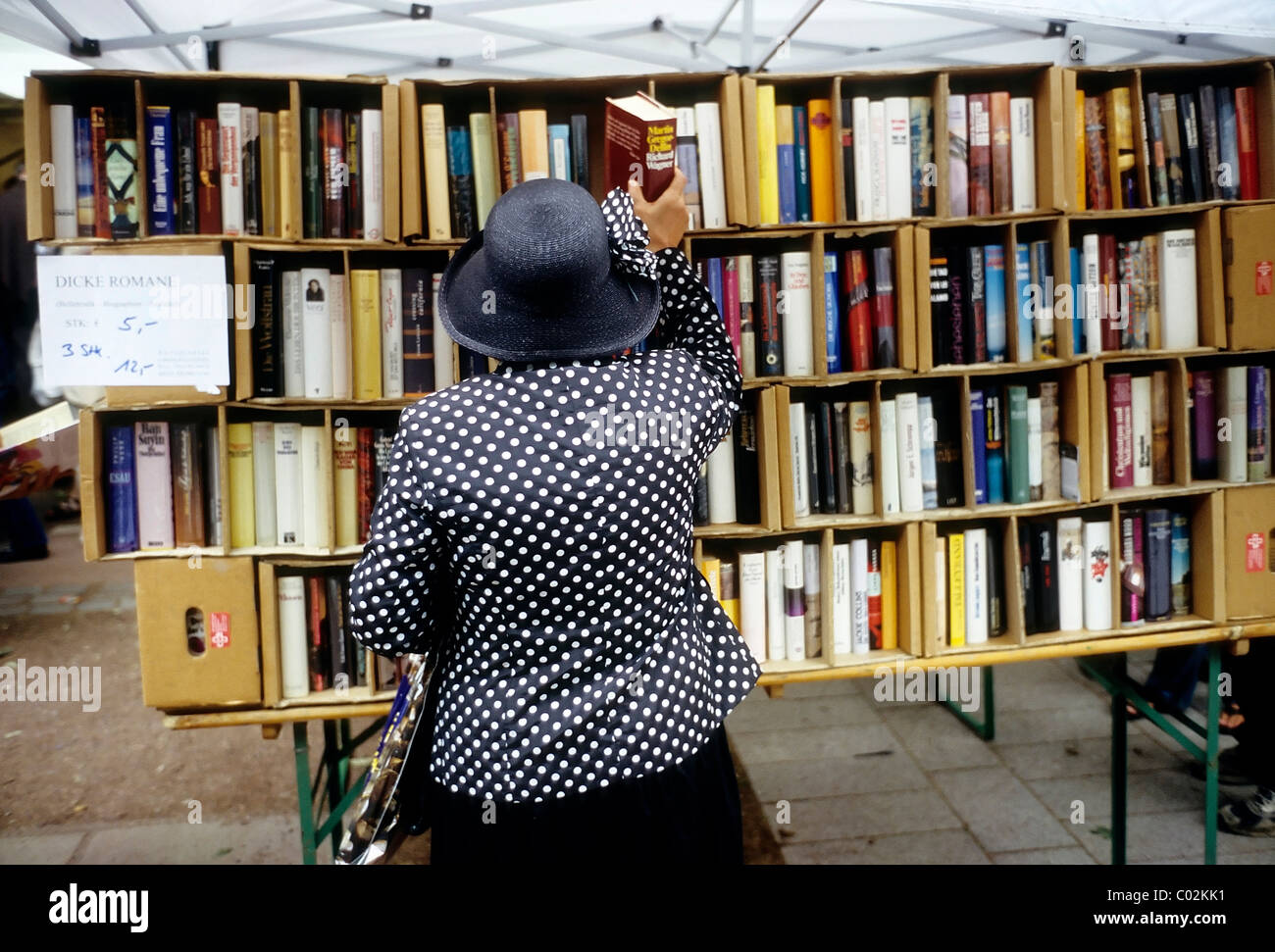 Elderly lady taking a thick novel from store shelf, open-air book market, Koenigsallee, Duesseldorf, North Rhine-Westphalia Stock Photo