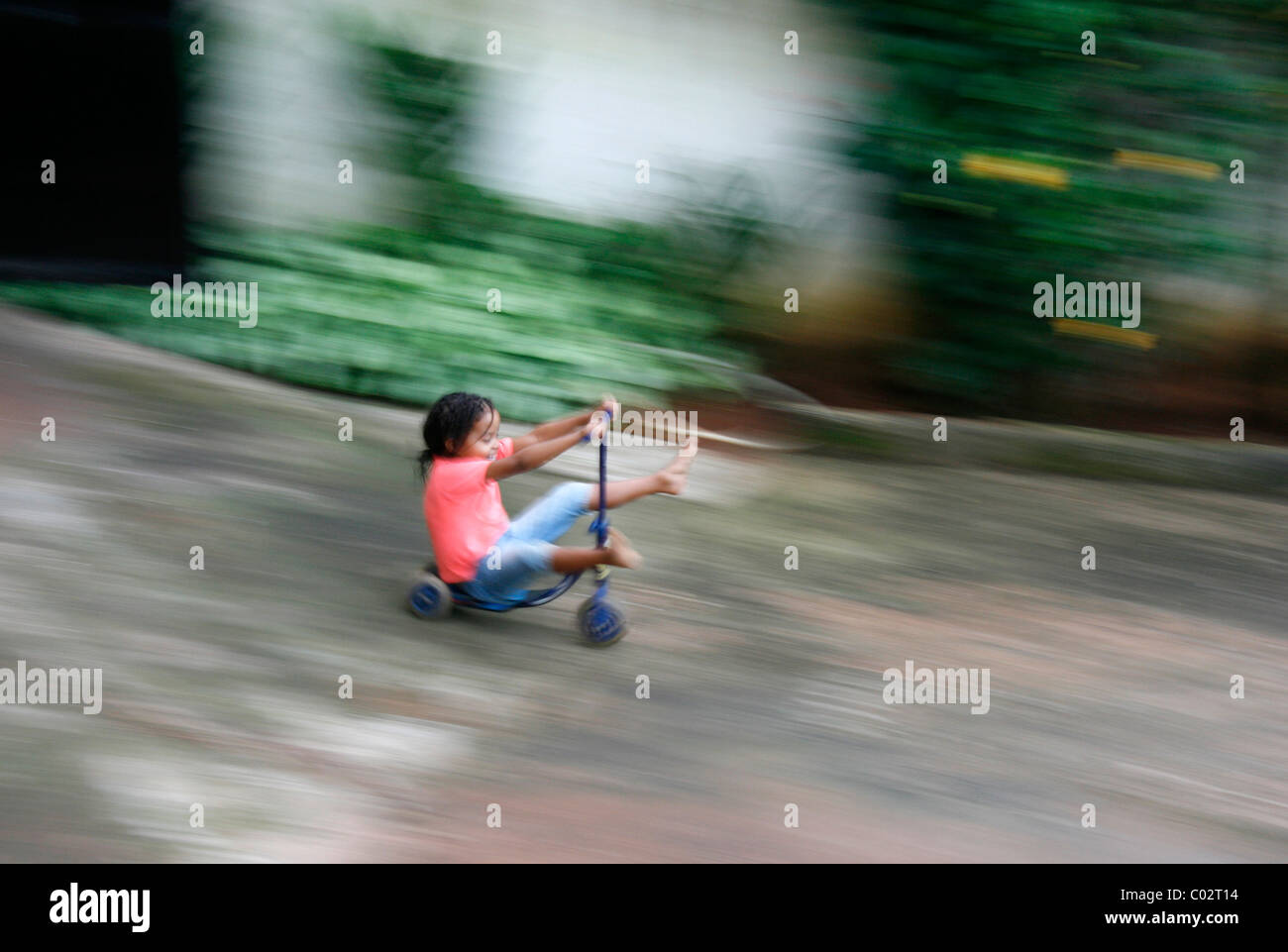 A young girl riding her scooter down a small hill Stock Photo Alamy