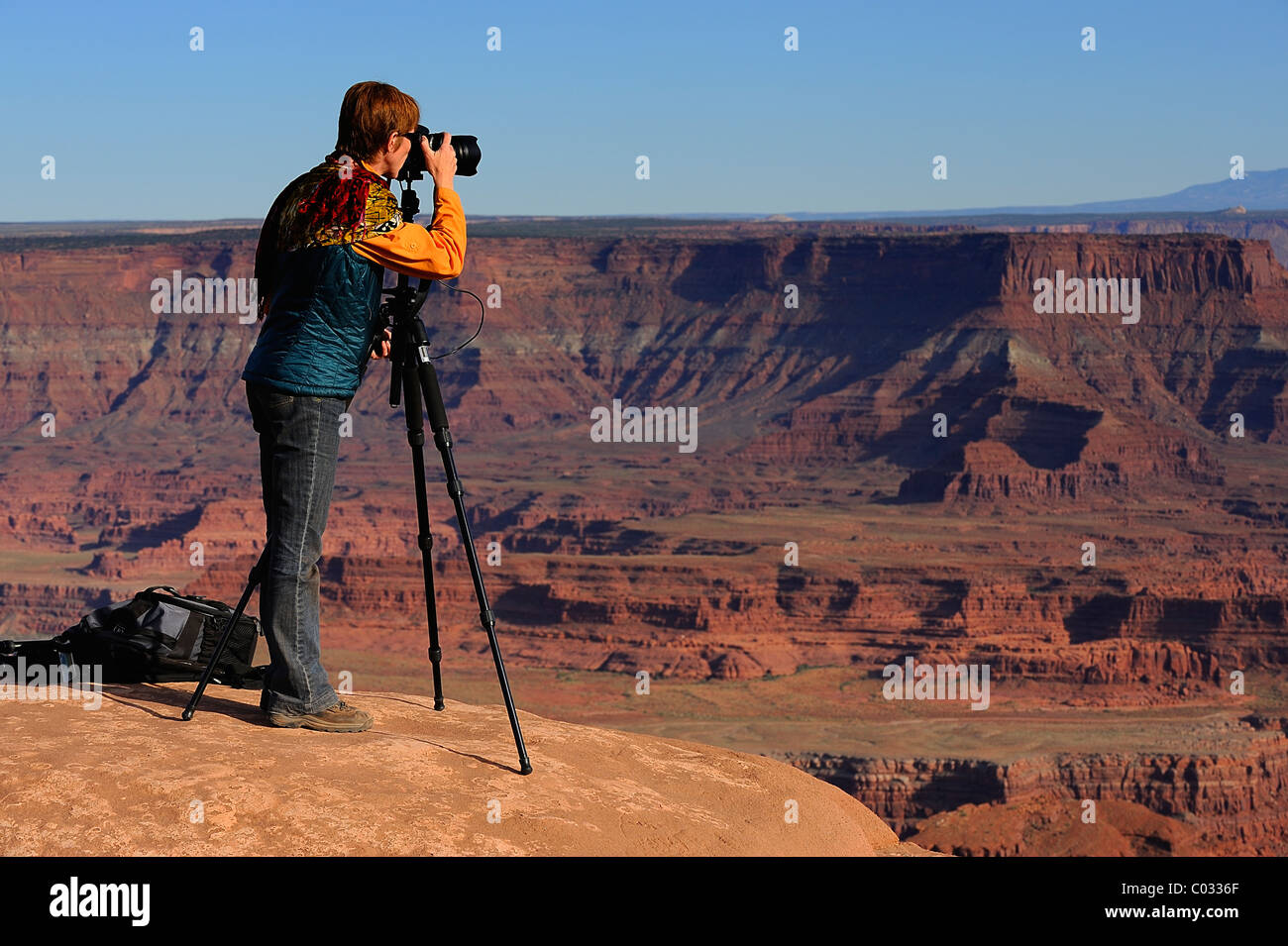 Woman photographer taking a picture with a SLR mounted on a tripod in Canyonlands National Park, Island in the Sky, USA Stock Photo