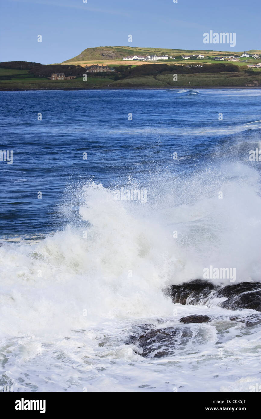 Waves crashing against the rocks of Portballintrae looking toward Runkerry House, County Antrim coast, Northern Ireland Stock Photo