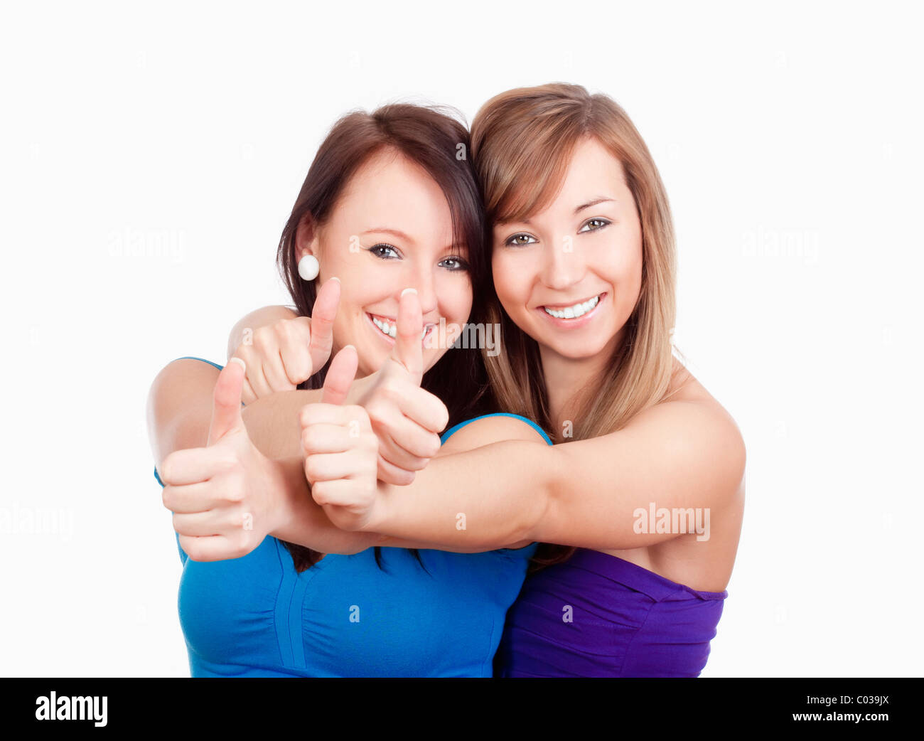 two young women showing thumbs up, smiling - isolated on white Stock Photo