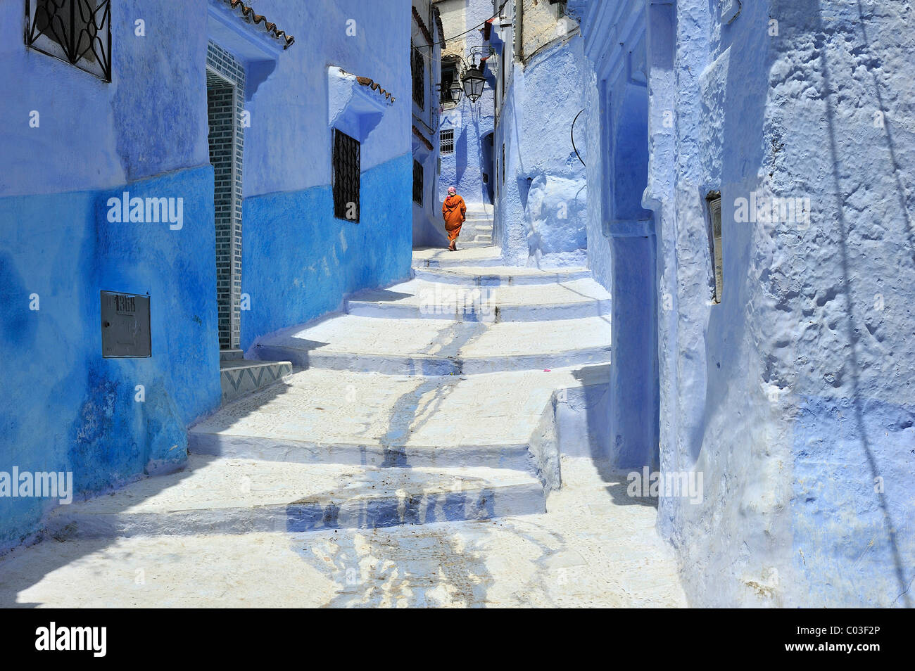 A woman walking in an alleyway painted blue in the medina of Chefchaouen, Morocco, Africa Stock Photo