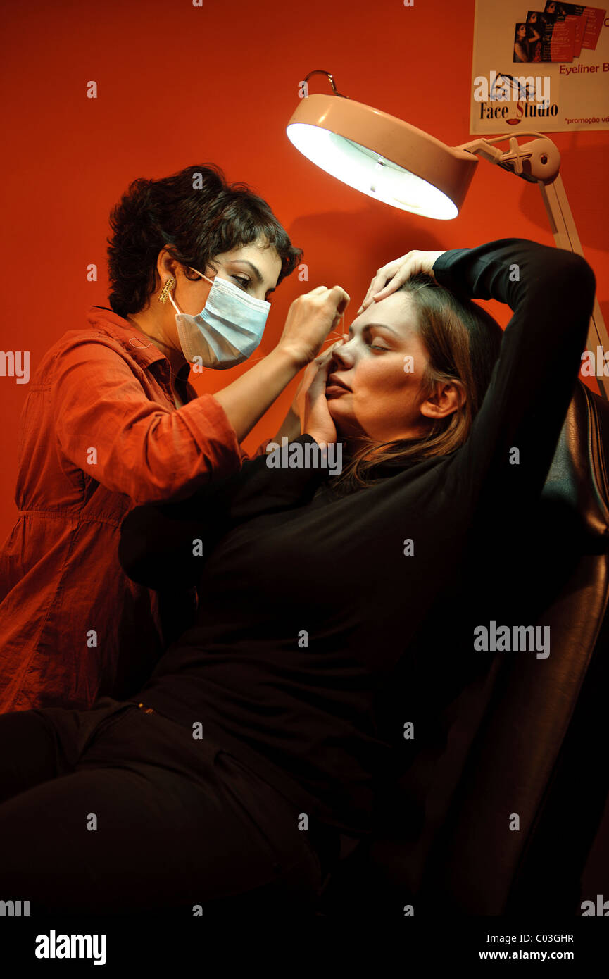 Beautician plucking client's eyebrows in an hair salon Stock Photo