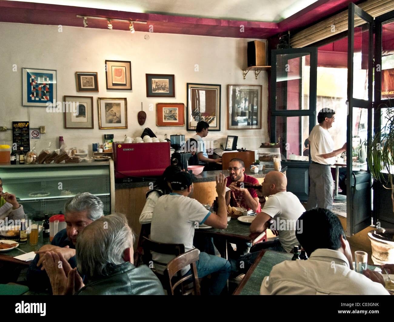 light filled interior of charming crowded art filled cafe with old world ambiance & conviviality Roma District Mexico City Stock Photo