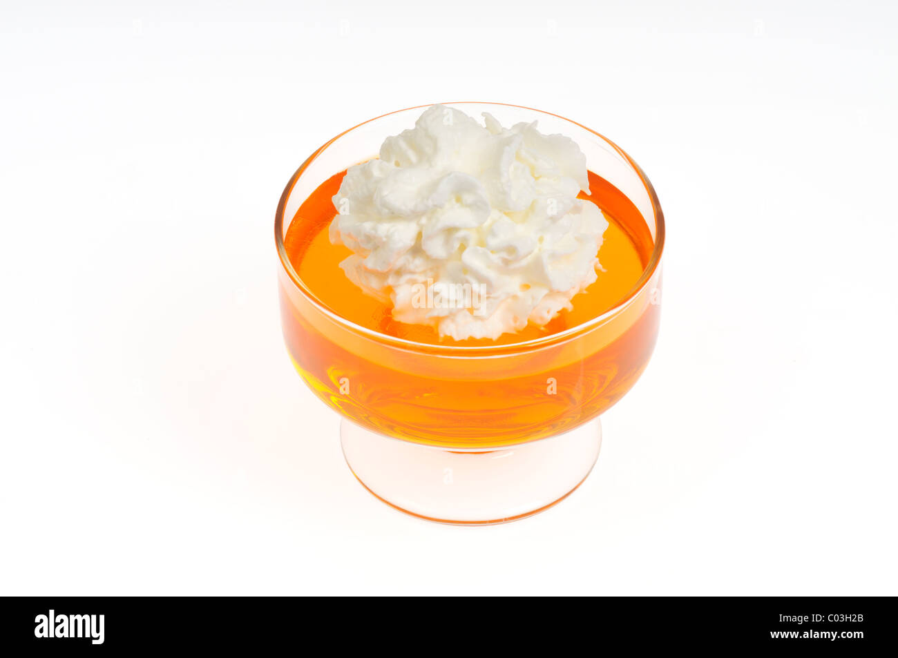 Orange Jell-O with whipped cream topping in glass serving dish on white background, cutout Stock Photo