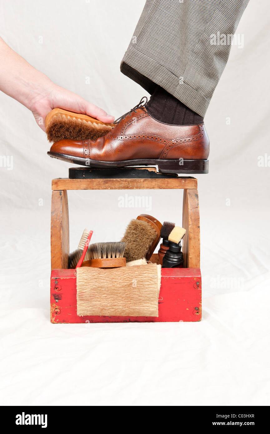 A man gets his shoes polished by a worker using a vintage shoe shine box Stock Photo