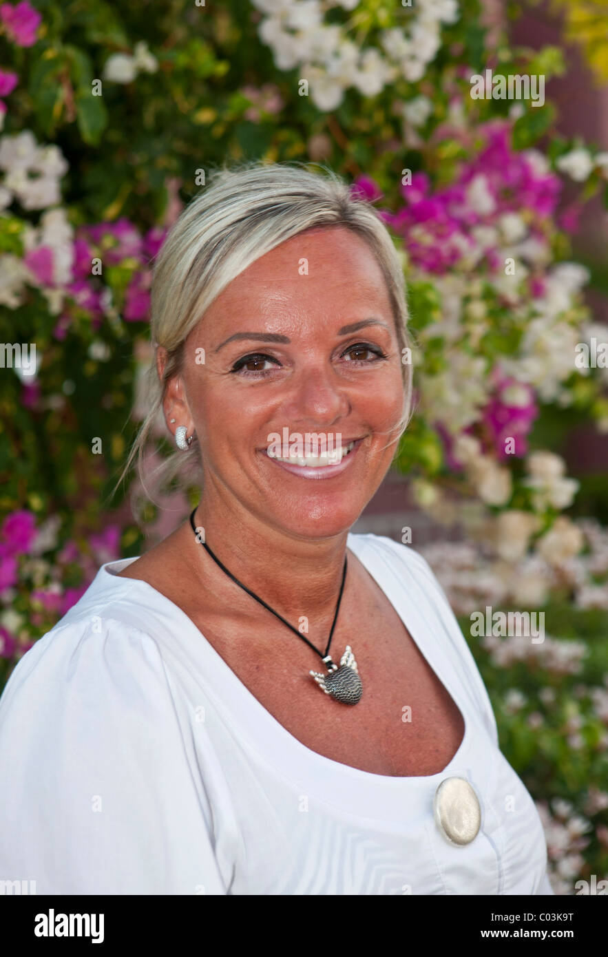 Portrait of a forty-year-old woman in front of flowers Stock Photo