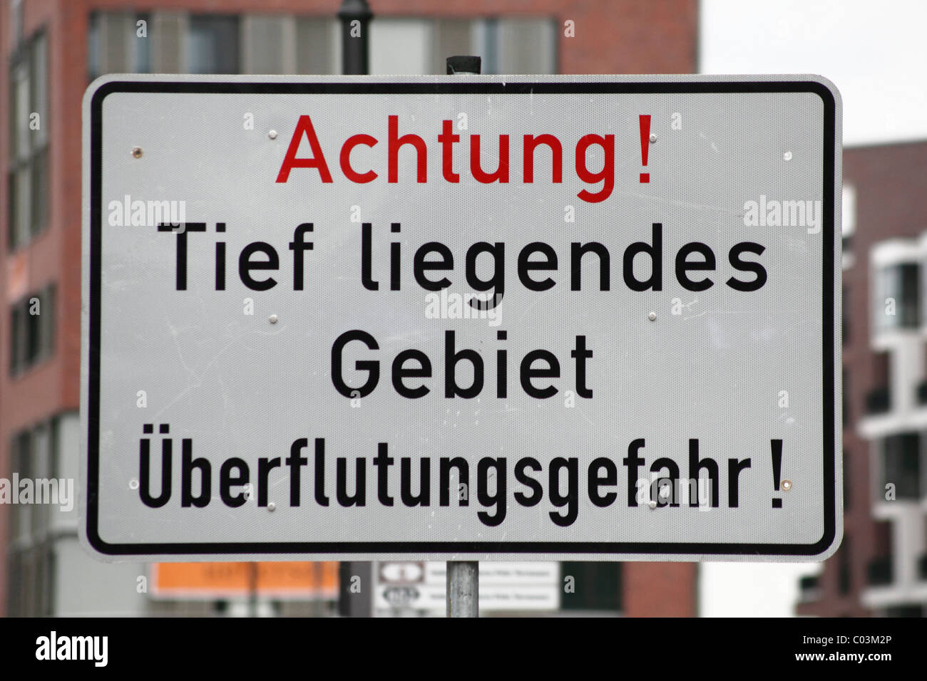Warning sign 'Achtung! Tief liegendes Gebiet, Ueberflutungsgefahr!', German for 'Caution! Low-lying area, danger of flooding!' Stock Photo