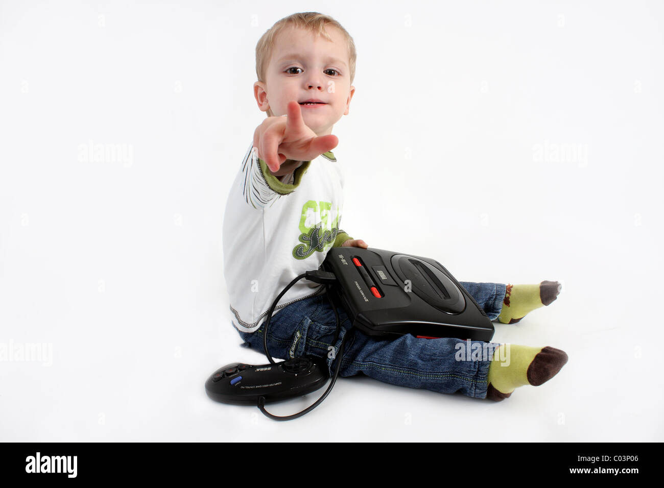 A young toddler boy playing with an old retro gaming video games console system called the Sega Mega Drive 16 Bit edition Stock Photo