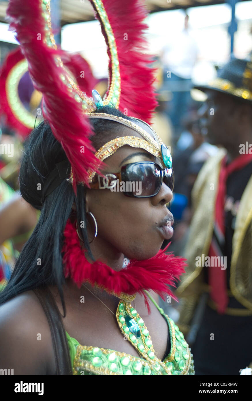Woman dressed up with feather head gear wearing huge sun glasses at the Notting Hill Carnival, London Stock Photo