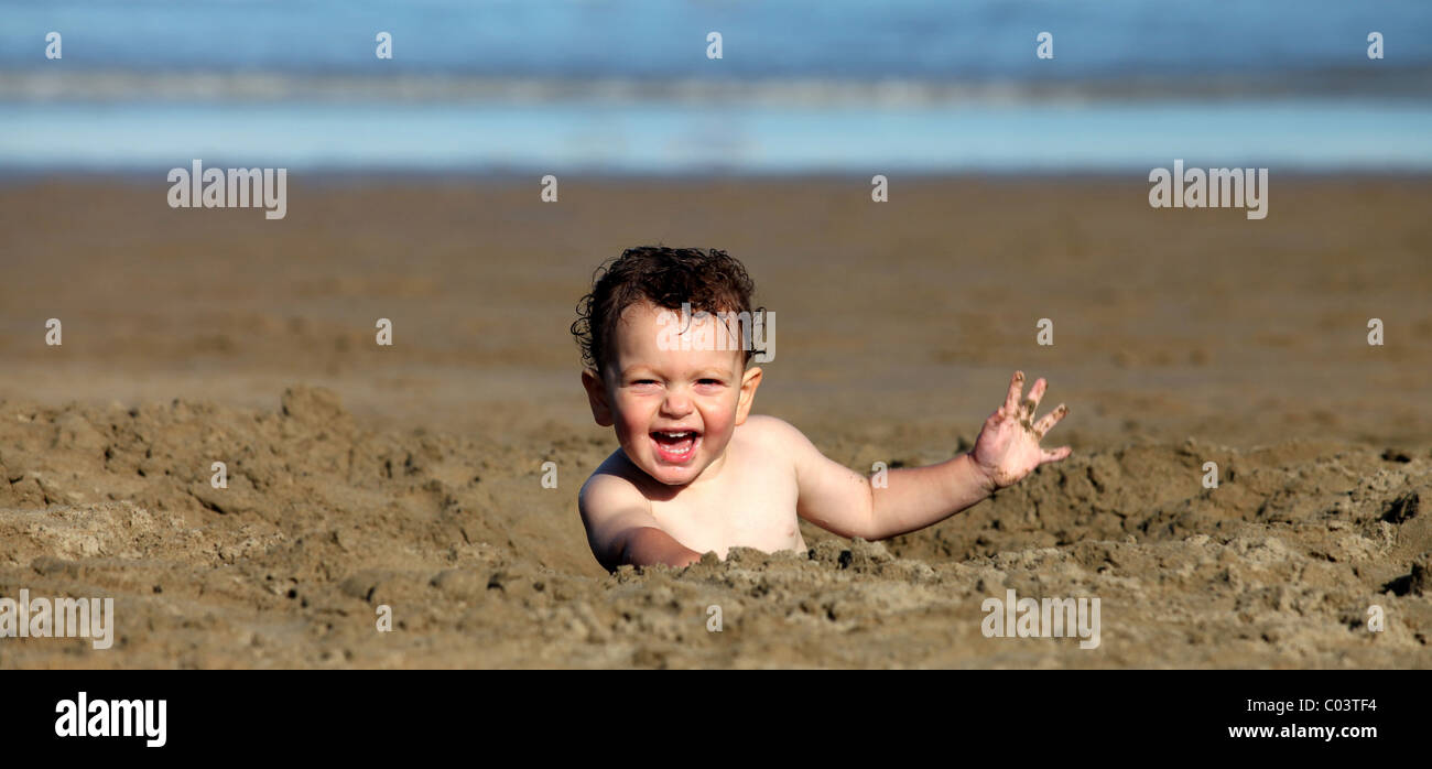 A young boy is playing in the sand at the beach. Stock Photo