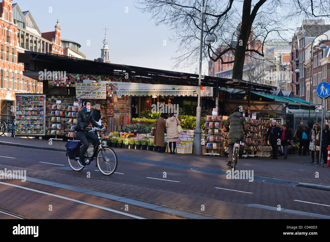 Cyclists pass the Bloemenmarkt Flower Market, Amsterdam Stock Photo Alamy