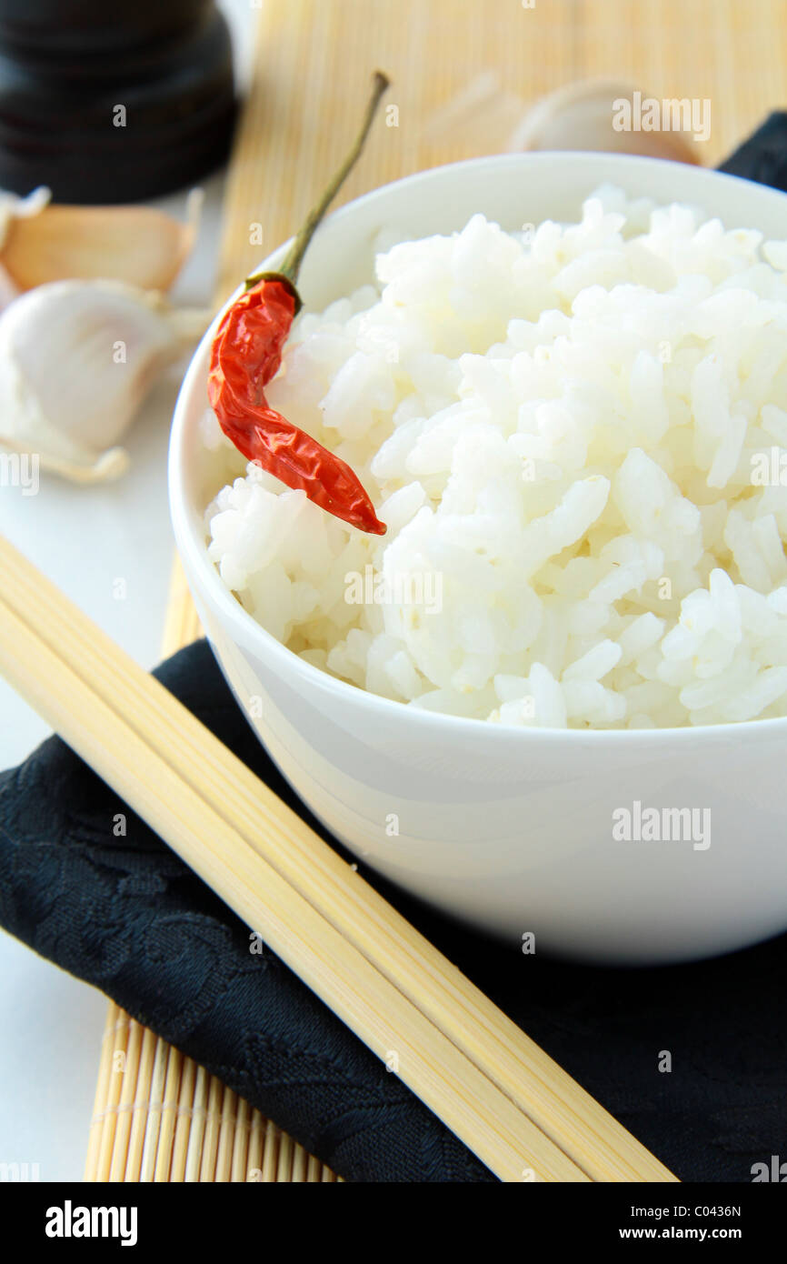bowl of white fluffy rice with chopsticks and bamboo placemat Stock