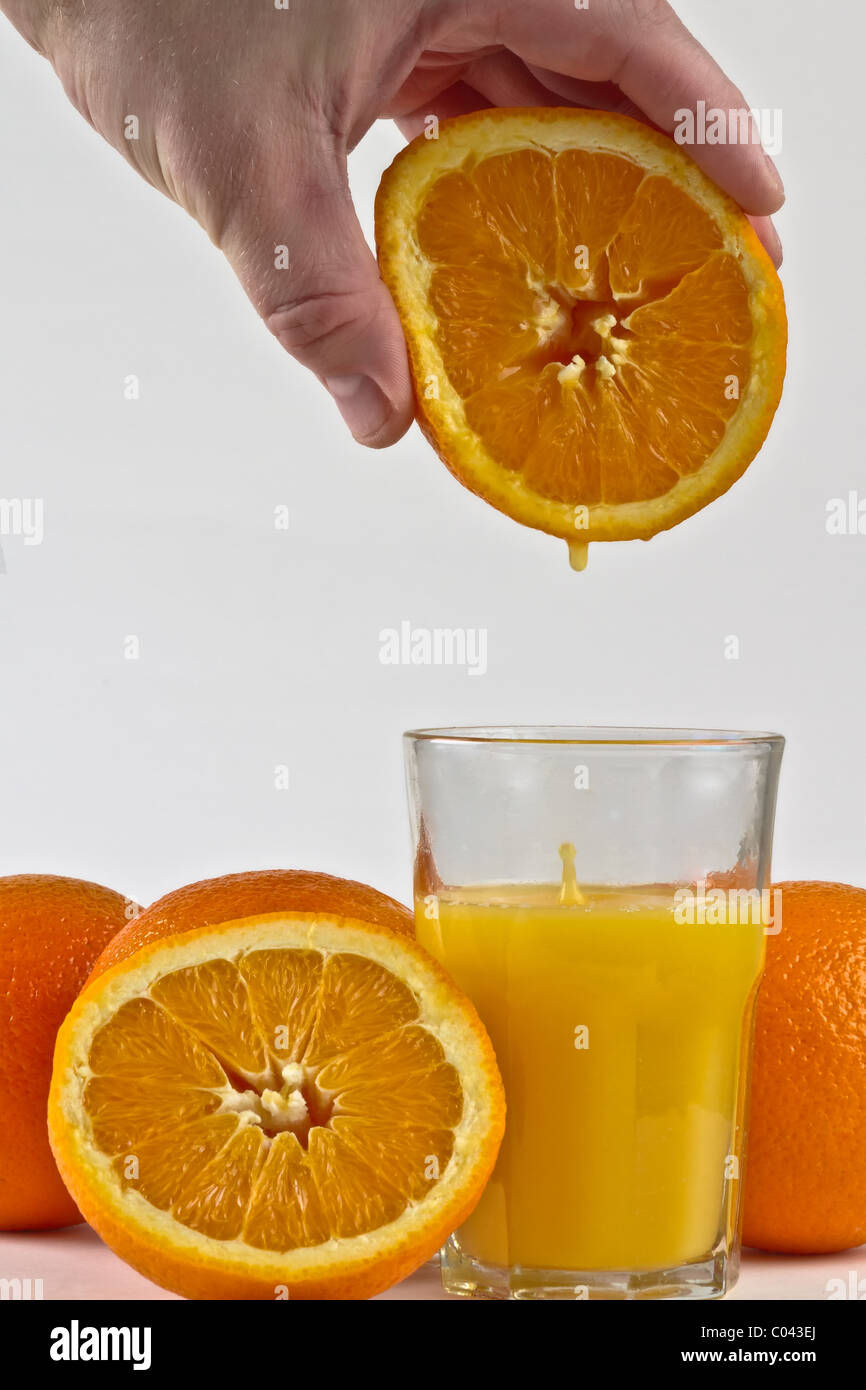 Fresh orange juice driping into glass from orange fruit. Stock Photo