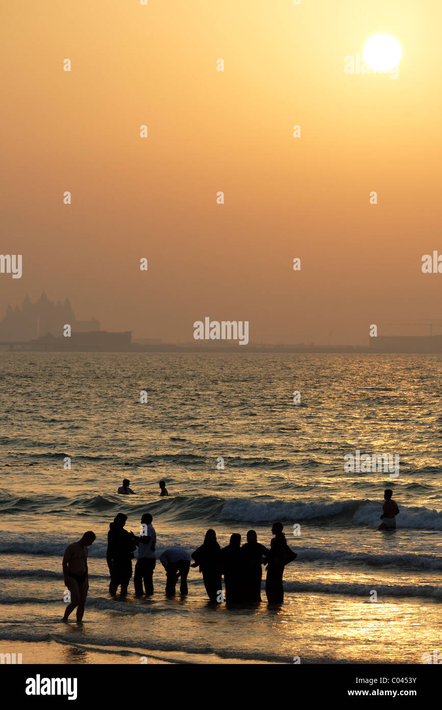 Fully dressed Arabic women on one of Dubai's public beaches - in the background the Atlantis hotel and other construction work Stock Photo