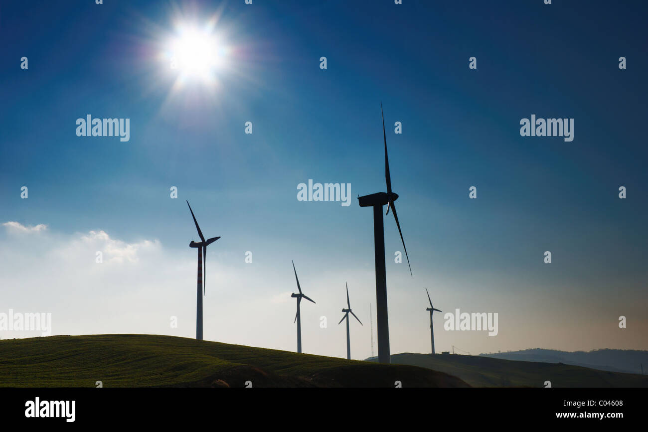 Four wind turbines silhouettes on top of hill Stock Photo - Alamy
