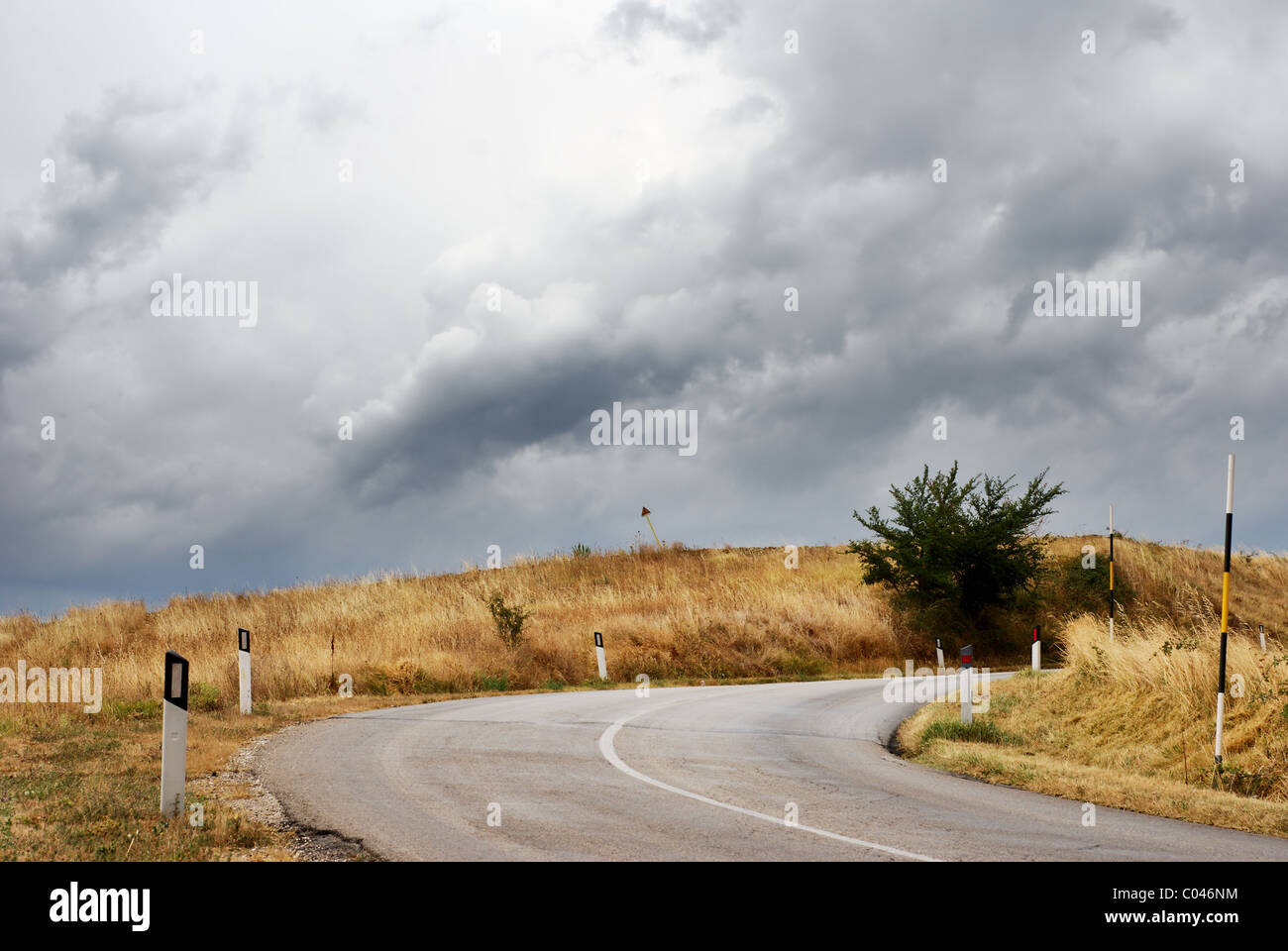 Country road curve in dark stormy wether Stock Photo