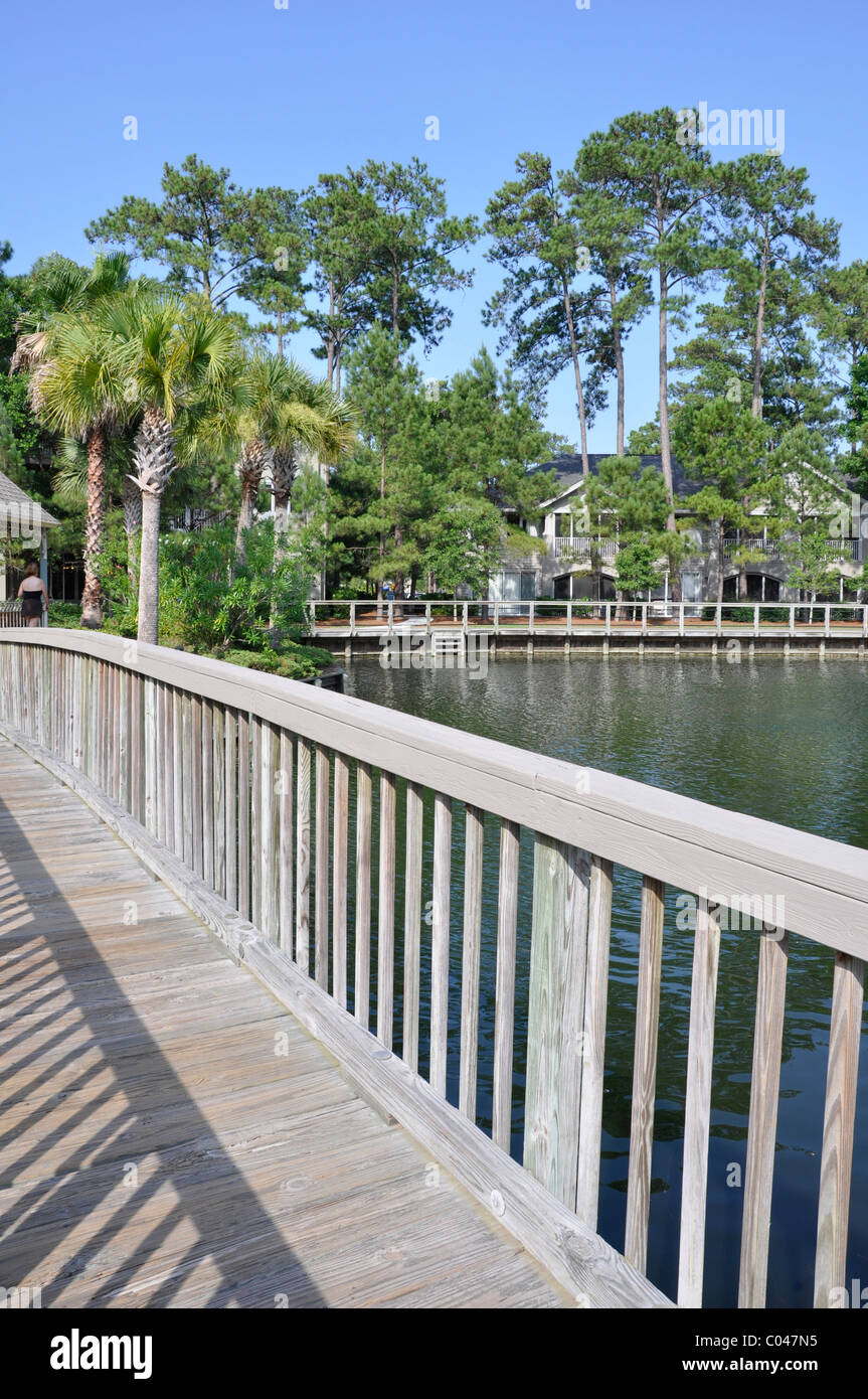 Wooden pedestrian walking bridge by a lagoon.  The setting is in Hilton Head Island in South Carolina.  The sky is bright blue. Stock Photo