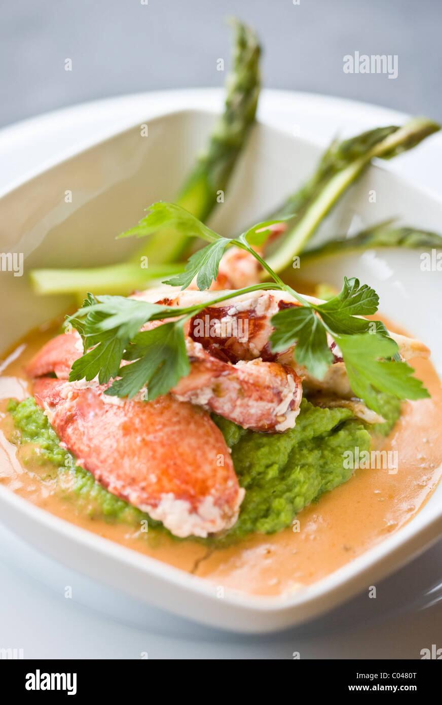 Crab claws peeled from their claws served on a bed of mashed peas and a reduced crab stock sauce Stock Photo