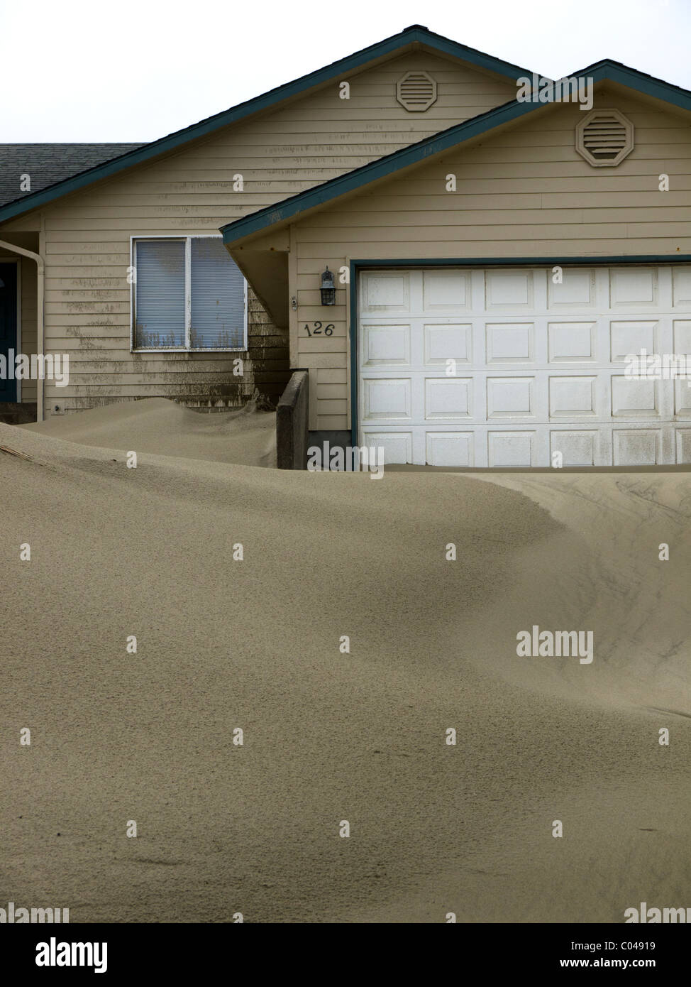 Sand dunes pile up around vacation homes after a storm on the Oregon coast . Stock Photo