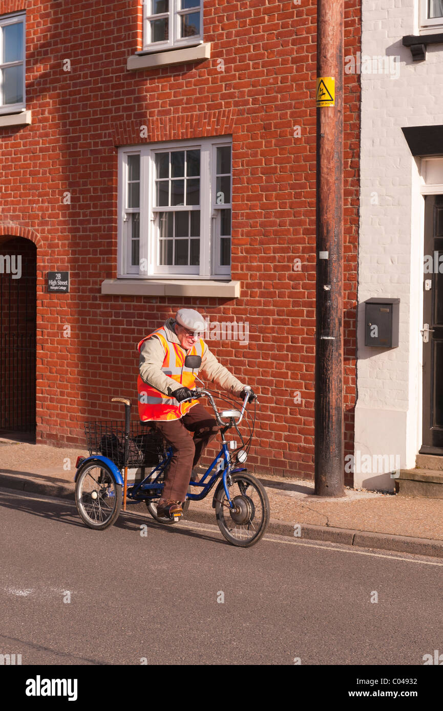 An elderly man cycling on a tricycle showing movement in the Uk Stock Photo