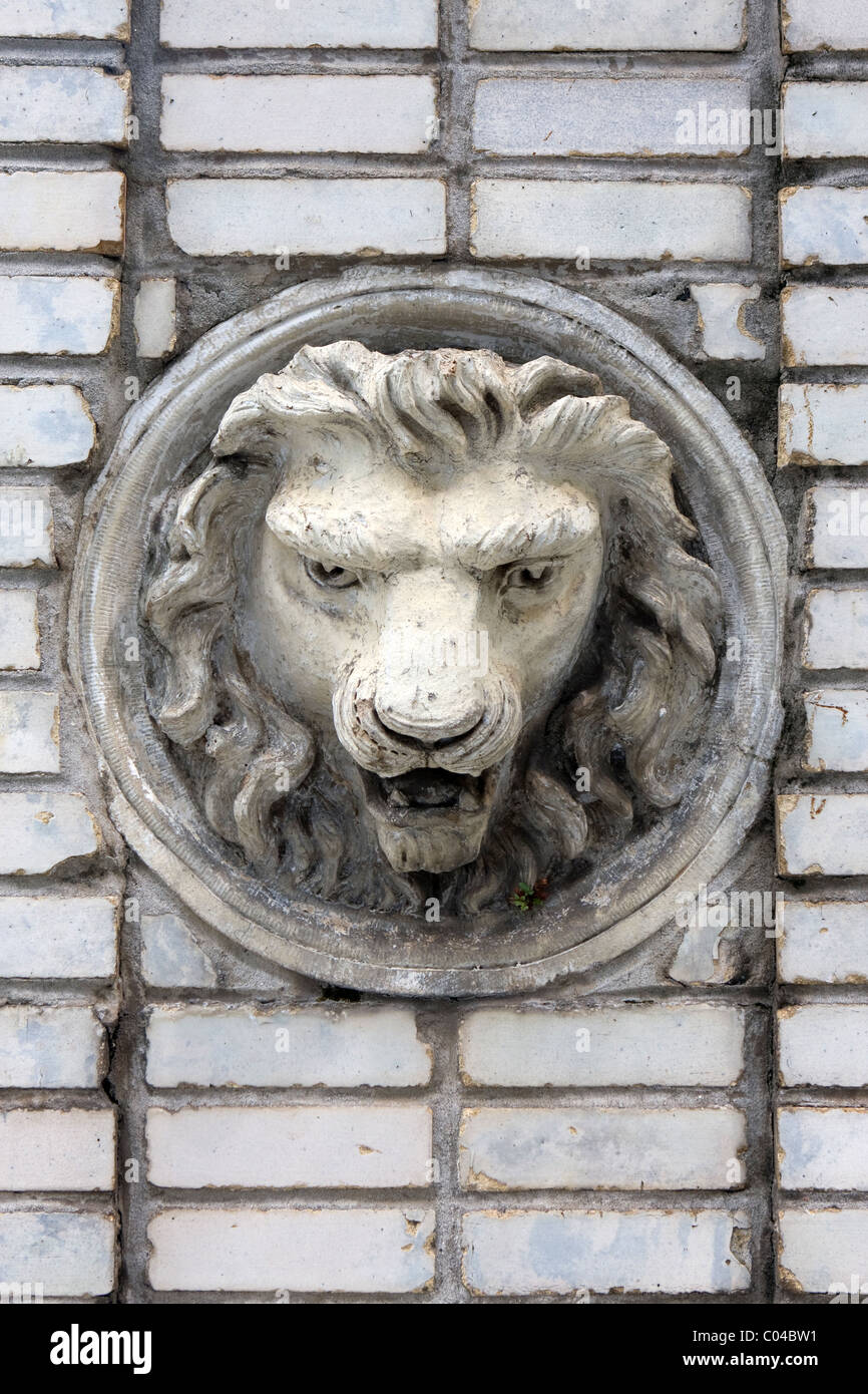 Vintage lion's head sculpted into a brick wall. Stock Photo