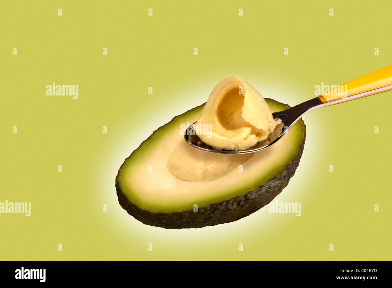 a avocado on a green background, with a spoon Stock Photo