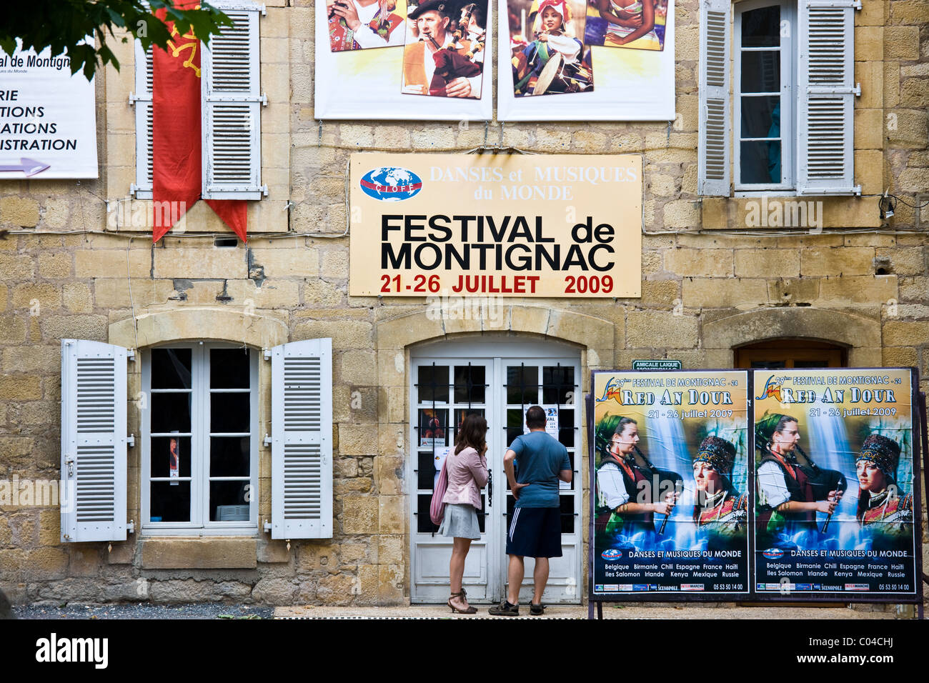 Young people reading festival poster about Festival de Montignac in the Dordogne, France Stock Photo