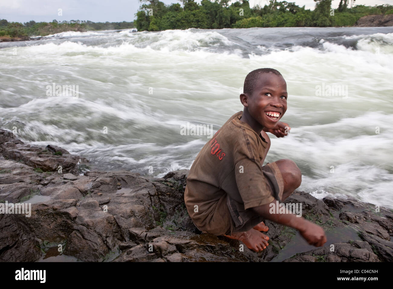 A school boy plays along the shores of the Nile River at Bujagali Falls, Uganda, East Africa. Stock Photo