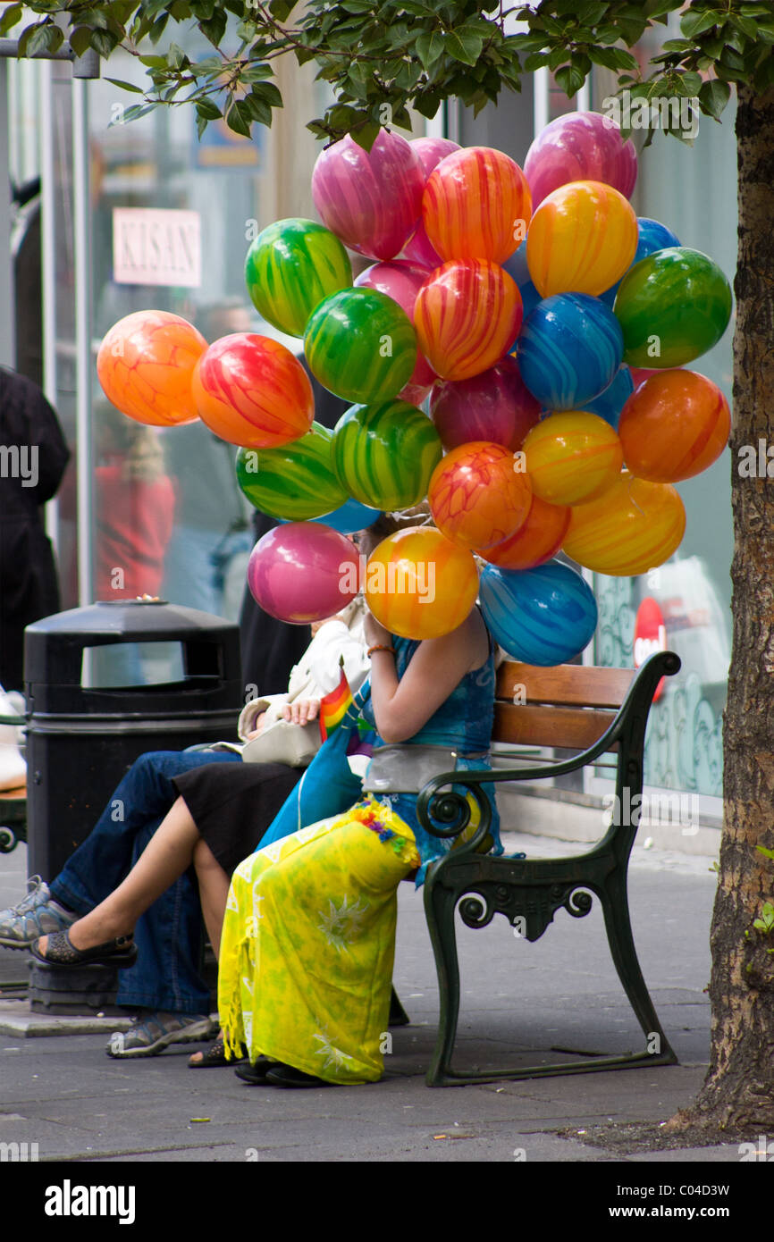 A person holding colorful balloons while a Gay Pride Parade goes past in Reykjavik, Iceland. Stock Photo