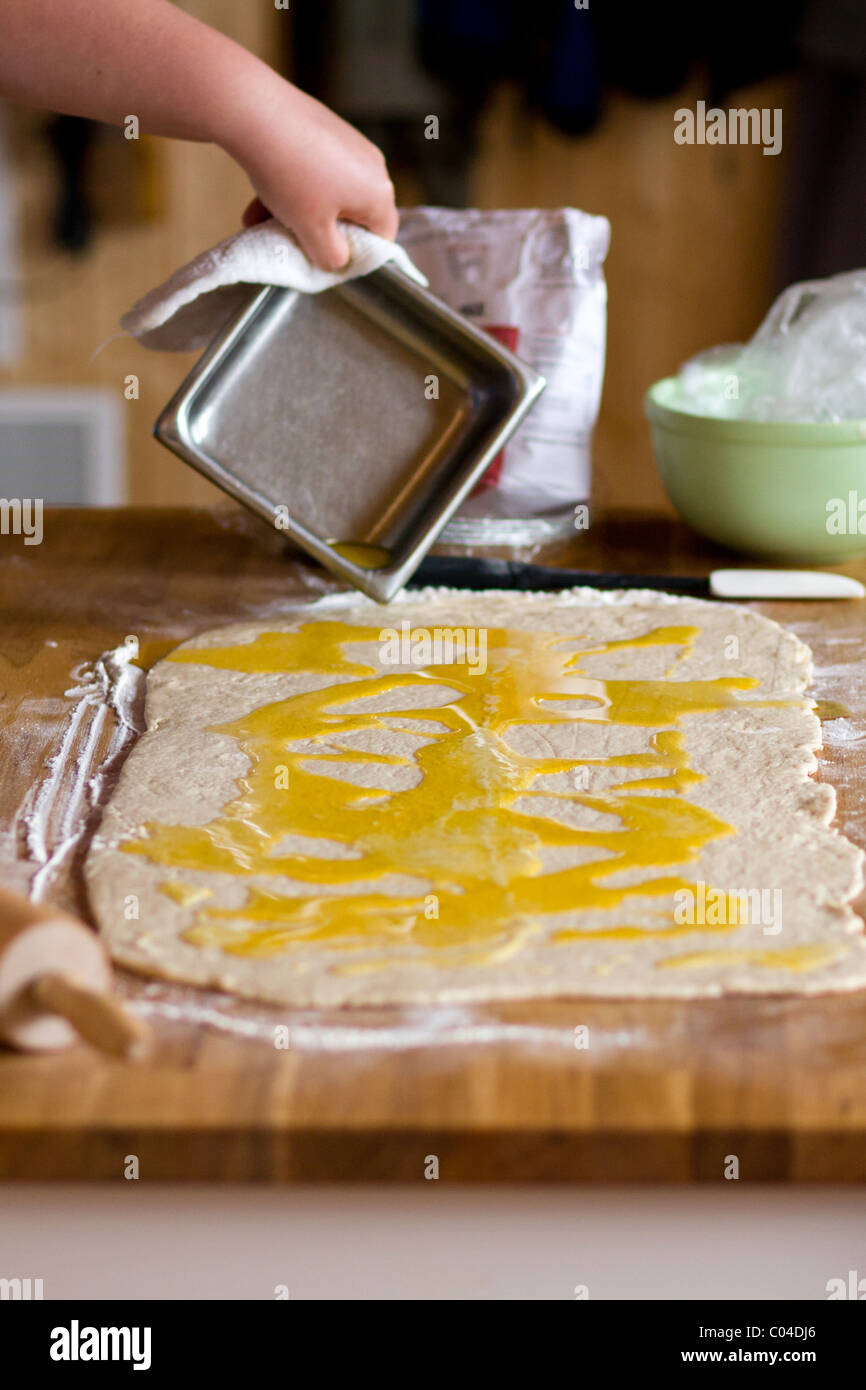 https://c8.alamy.com/comp/C04DJ6/woman-pouring-melted-butter-over-flattened-dough-preparing-cinnamon-C04DJ6.jpg