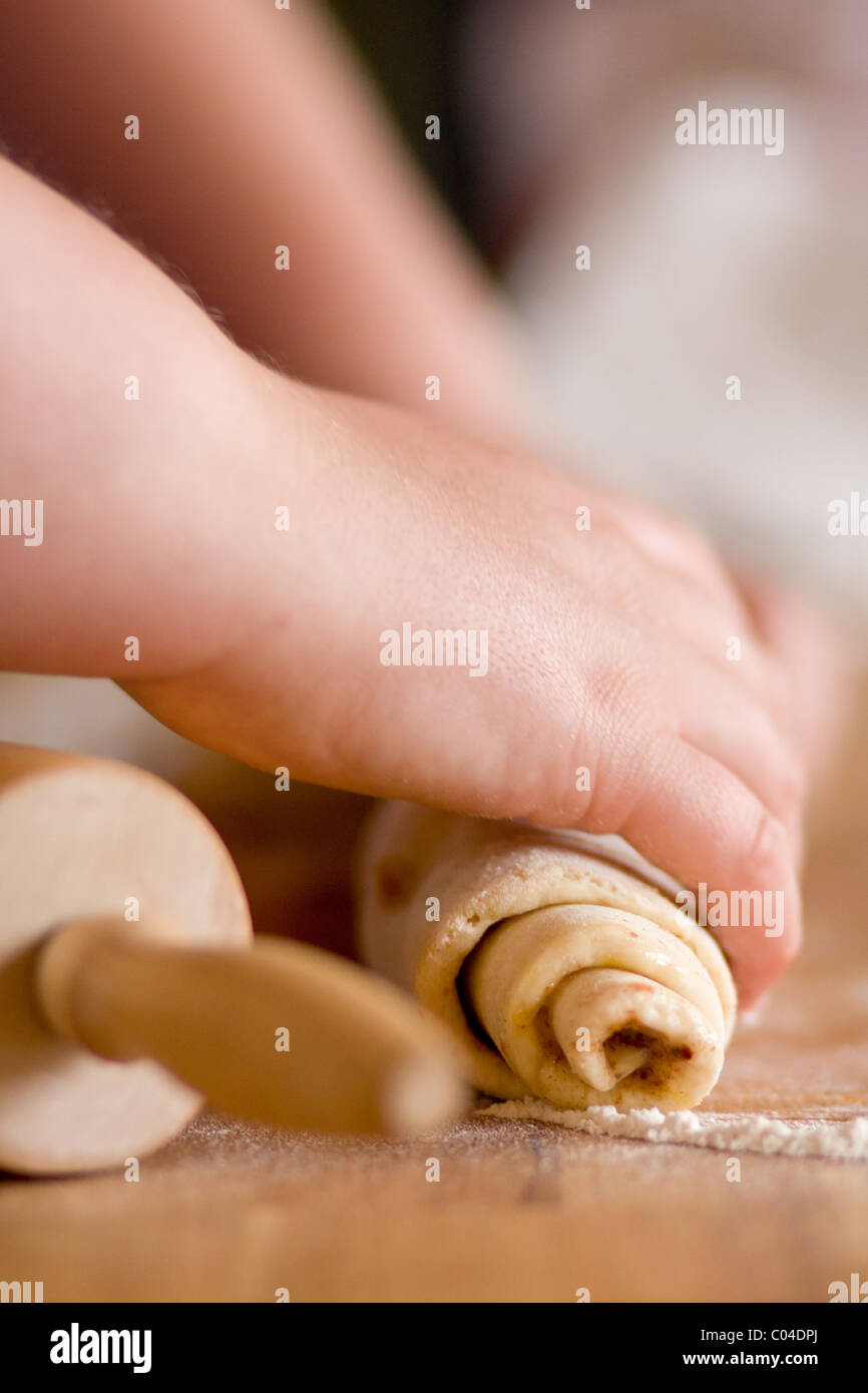 Woman rolling up dough to create cinnamon buns. Stock Photo
