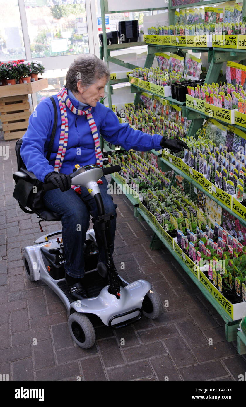 Mobility scooter user riding an ultra light battery powered machine in a garden centre The machine is self assembly Stock Photo