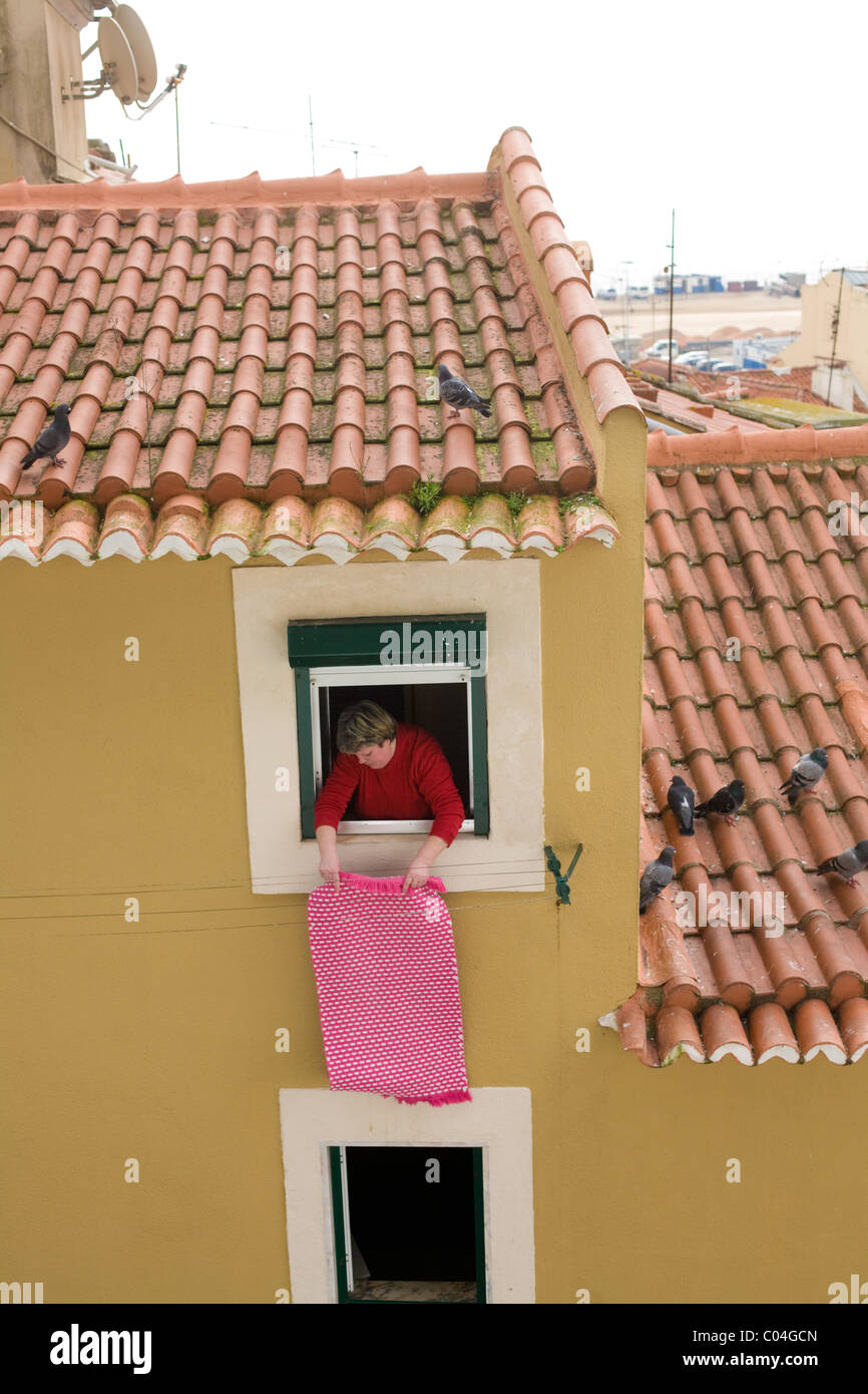 Woman shaking rug, the Alfama, Lisbon, Portugal Stock Photo