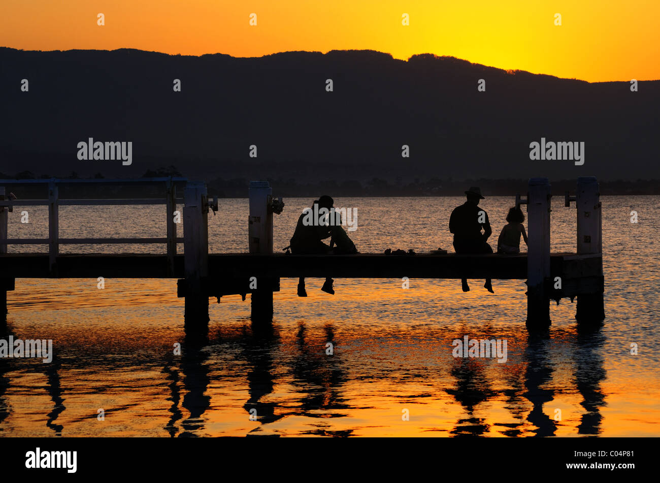 A family fishing from the jetty in Lake Illawarra at sunset, NSW