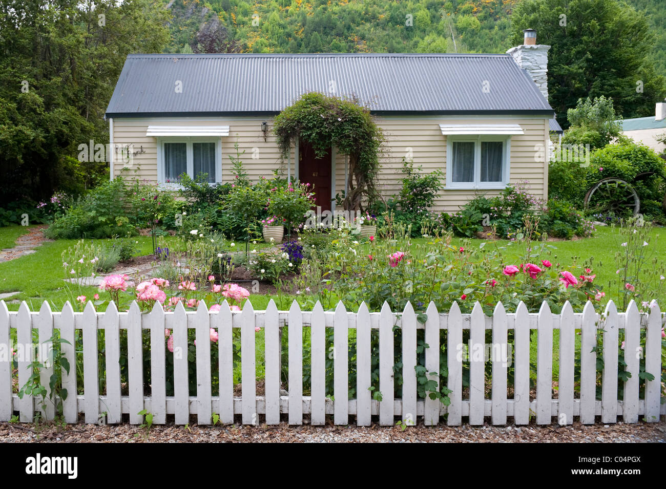 A simple weather boarded bungalow with rose garden and white picket fence at Arrowtown, New Zealand Stock Photo