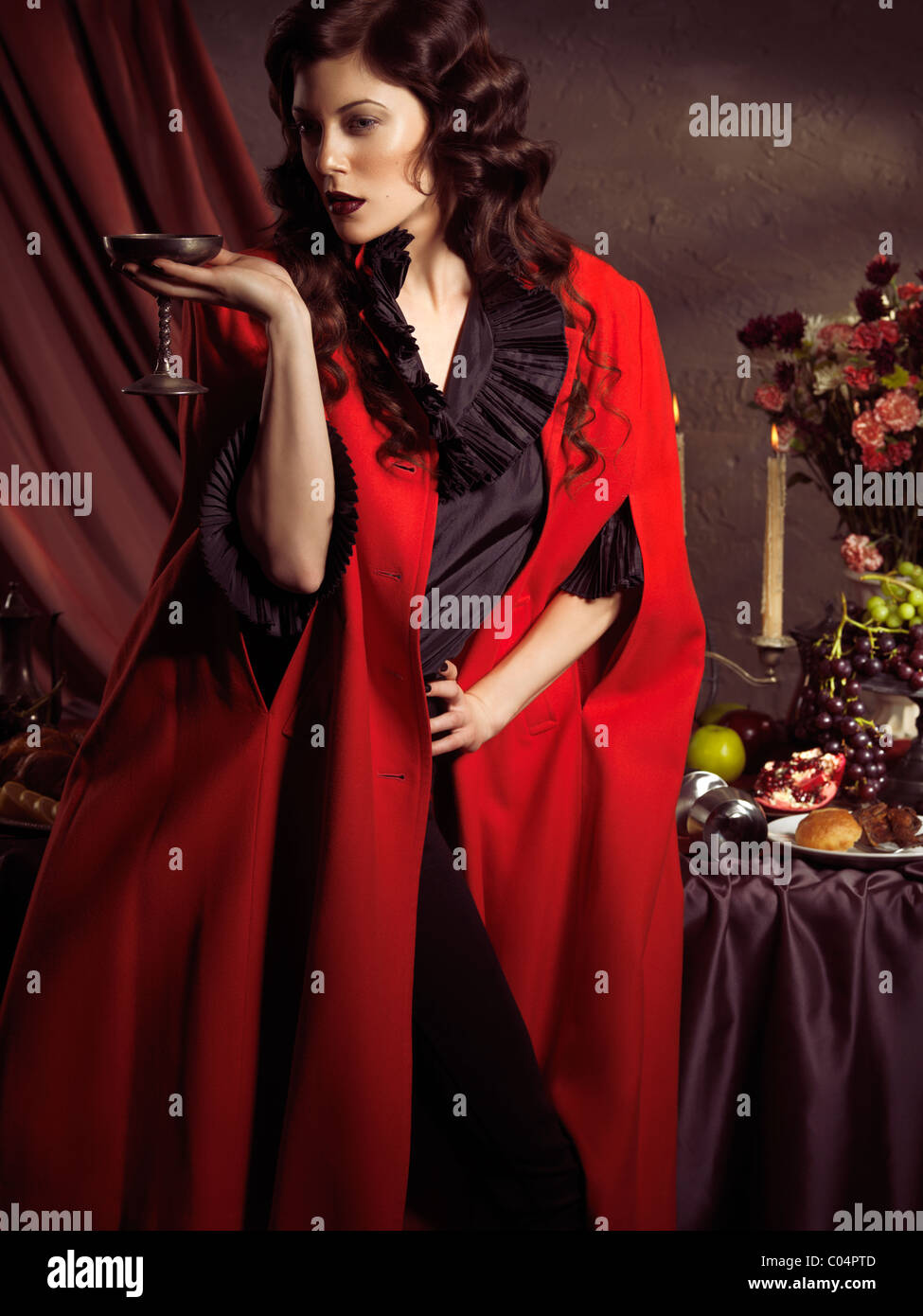 License and prints at MaximImages.com - High fashion photo of a beautiful woman standing with a glass of wine at a table with remains of a festive din Stock Photo