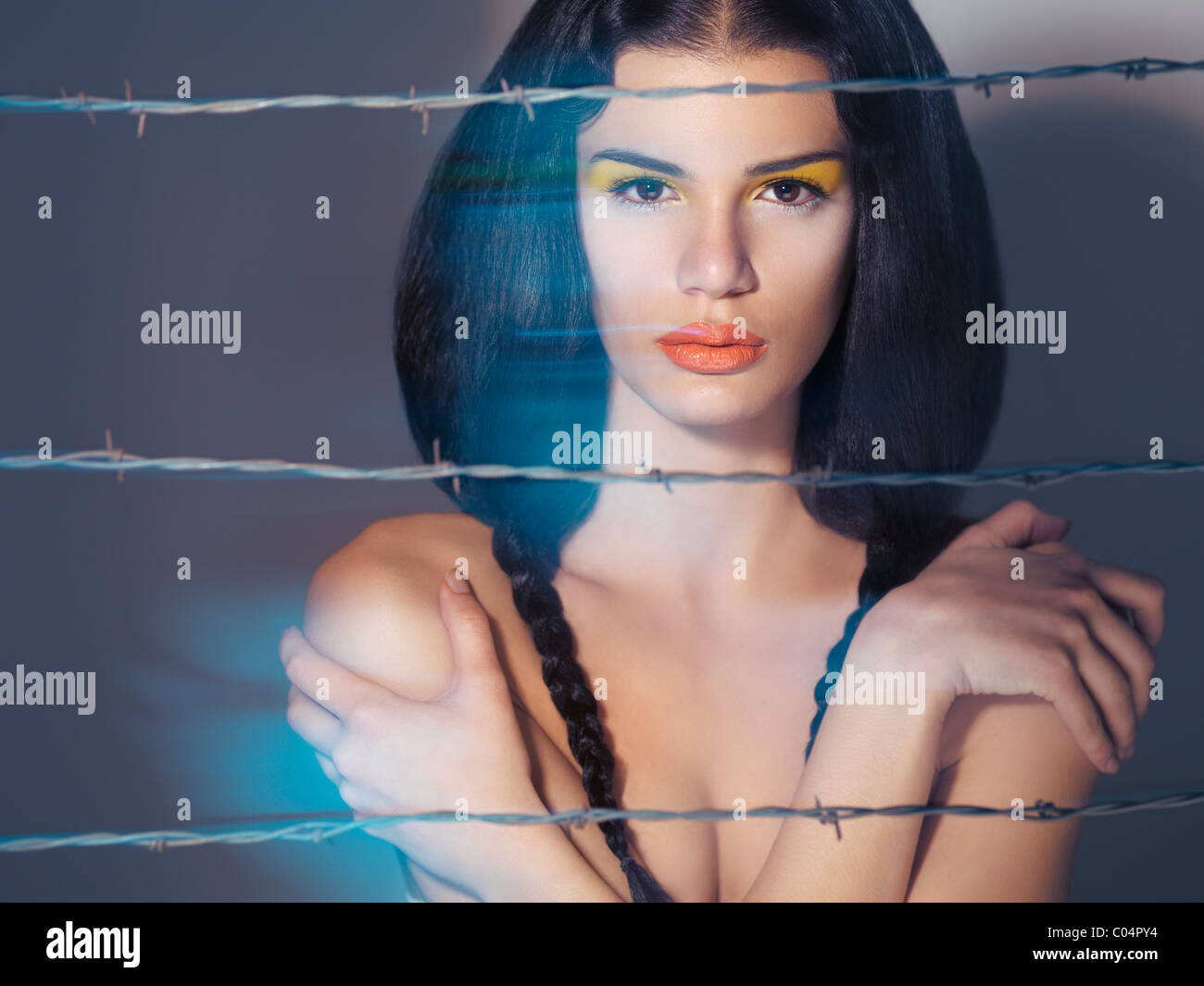 Artistic expressive beauty portrait of a young beautiful woman behind barbed wire Stock Photo