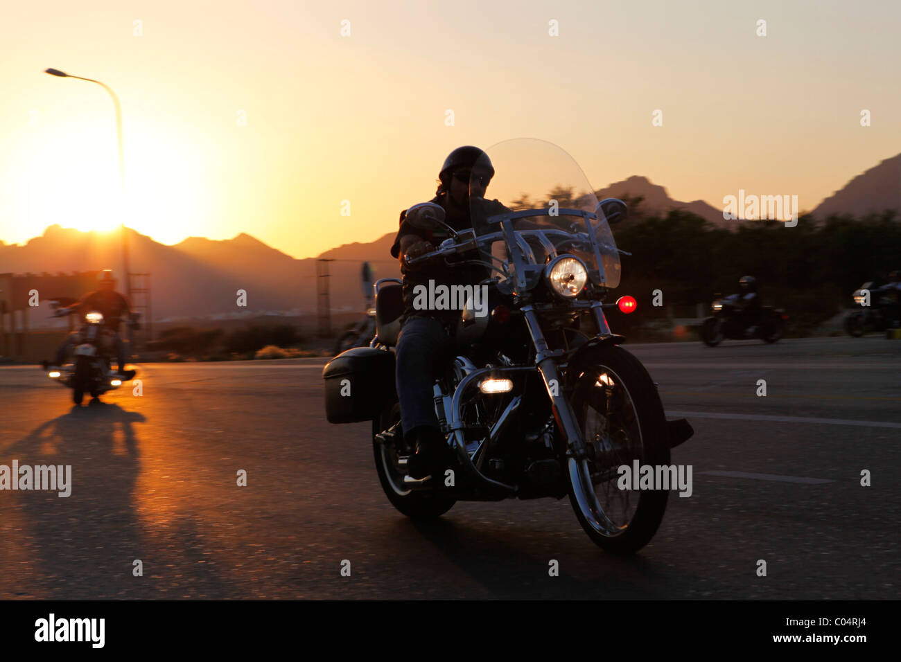 A group of Harley Davidson bikers rides out into the desert as the sun sets