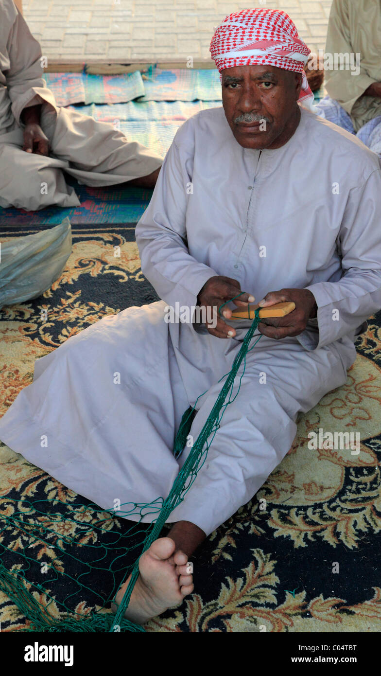 United Arab Emirates, Dubai, old man mending fishing nets, Stock Photo