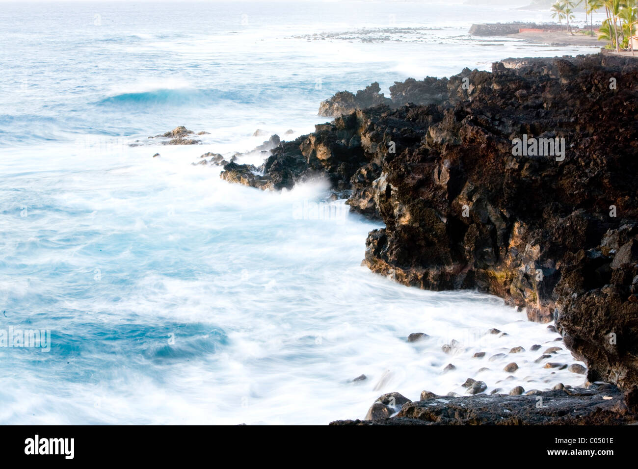 Time exposure turning surf against lava rocks in Kailua Kona Stock Photo