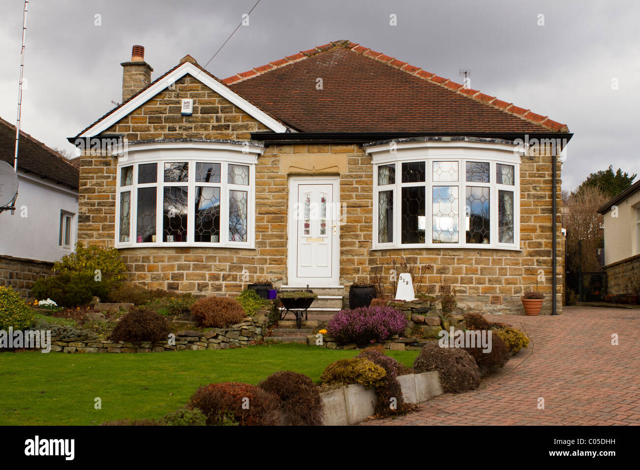 Well-maintained bungalow of stone with tiled roof, circa 1930s, with recent PVC doors and double-glazed windows. Stock Photo